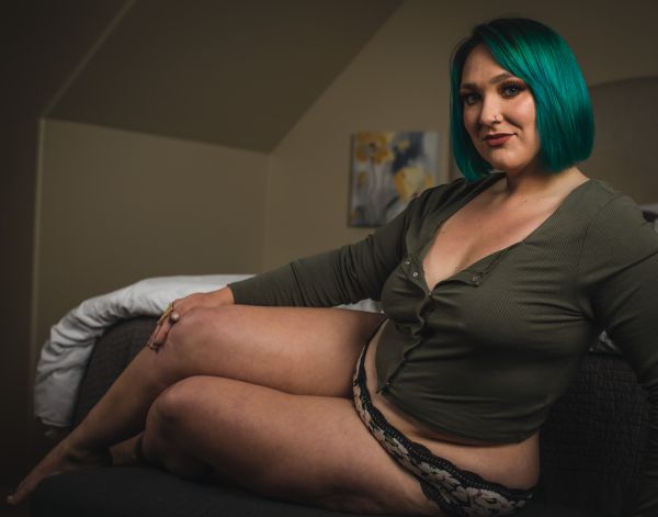 Reclining on a bedroom sofa in an open olive cardigan and floral lace panty