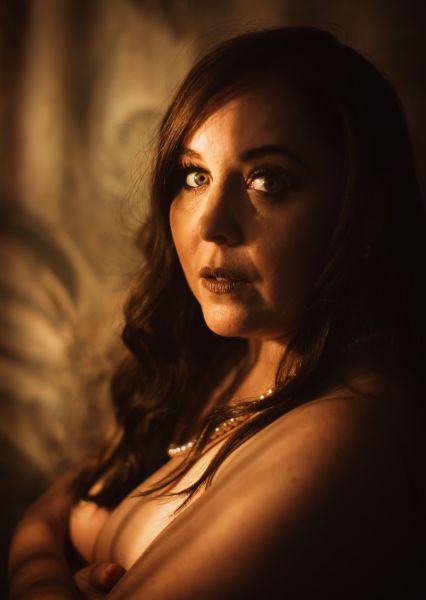 Close portrait in warm side lighting, pearl necklace against bare shoulders